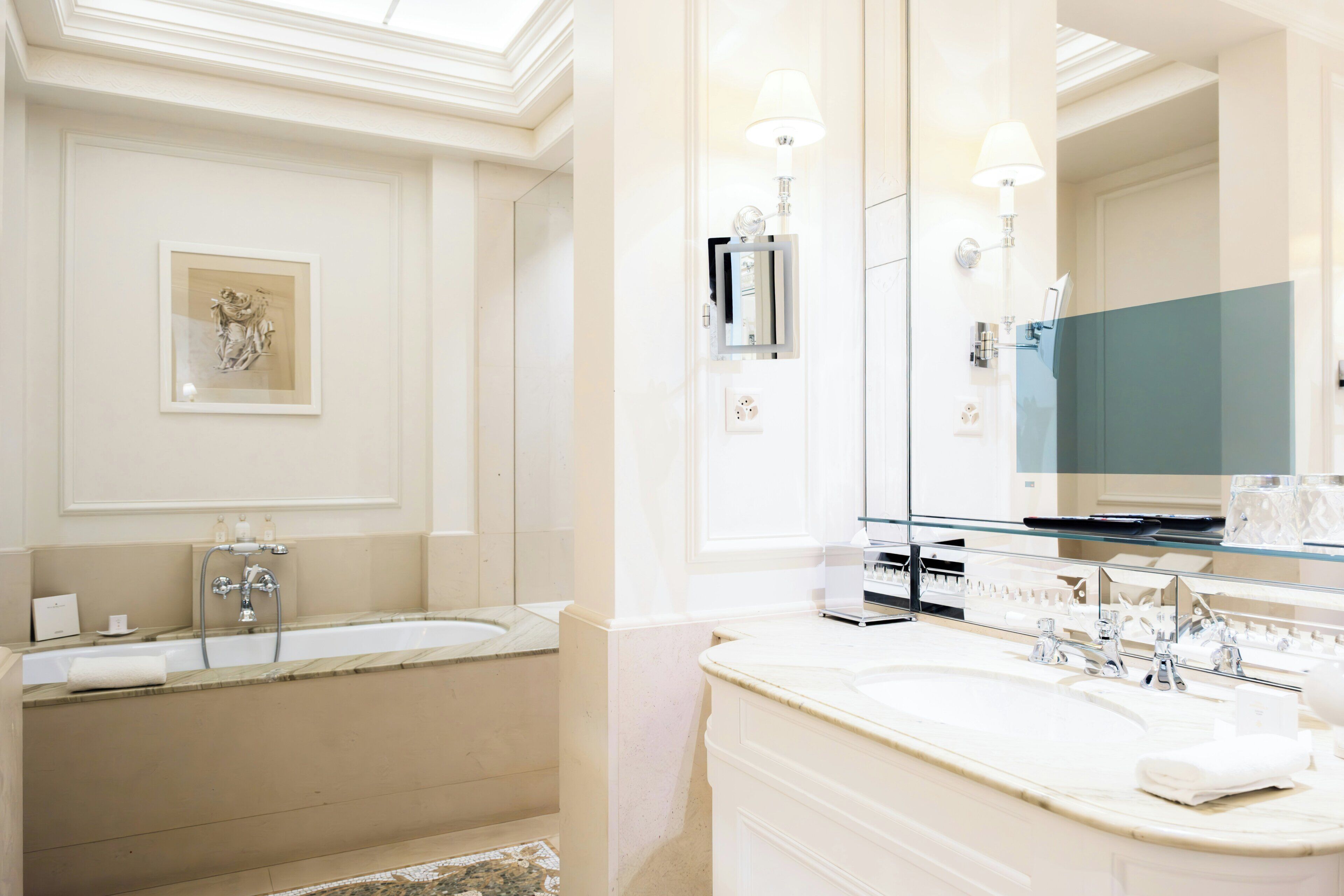 A bathroom with a bathtub, a large mirror, and a vanity with a sink.