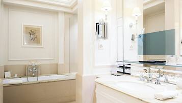 A bathroom with a bathtub, a large mirror, and a vanity with a sink.