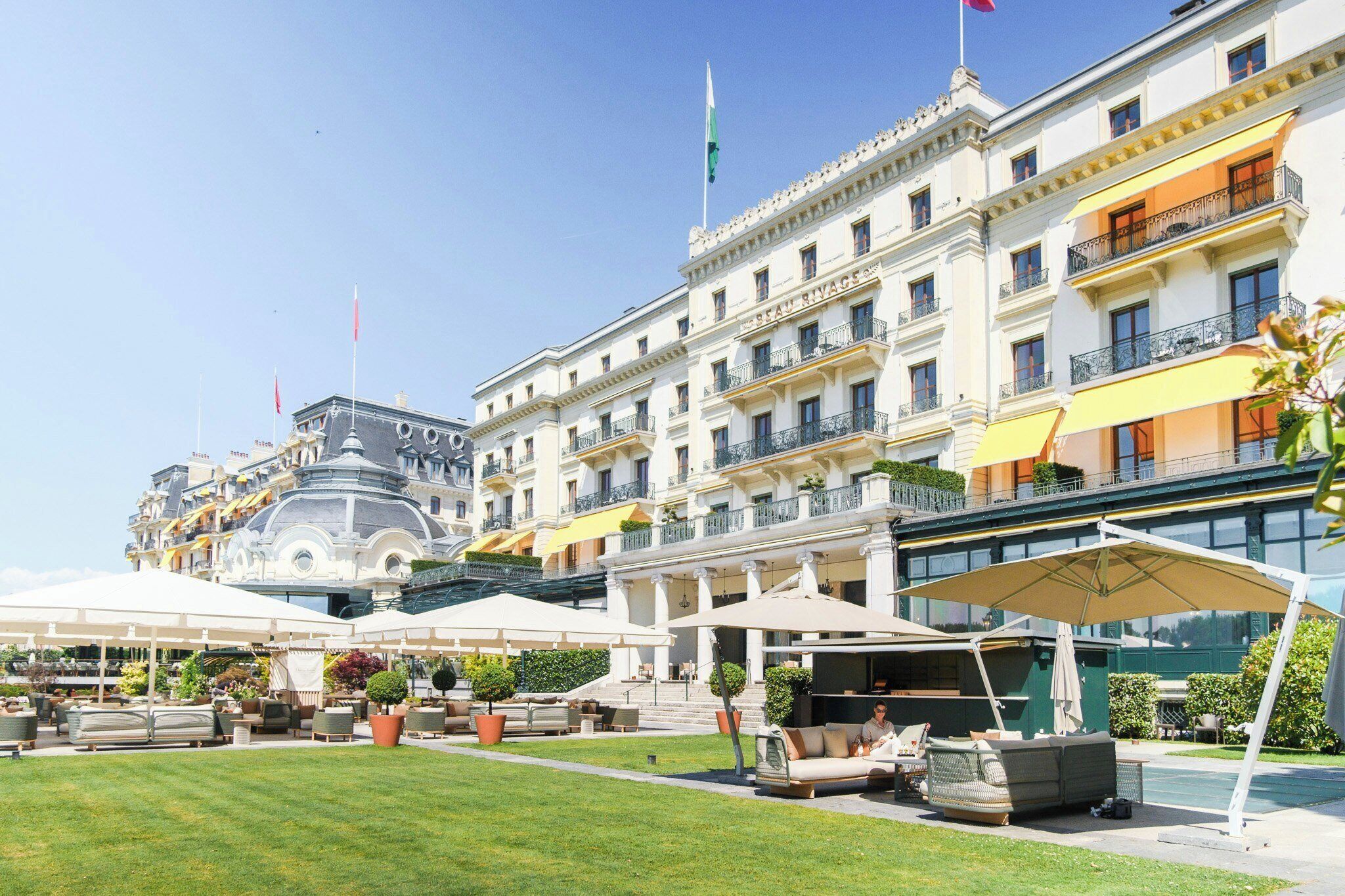 A hotel with outdoor seating, a fountain, and a well-maintained lawn.