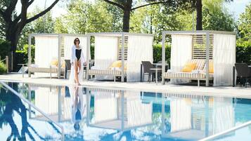 A poolside area with lounge chairs and a covered seating area.