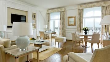 Amplia sala de estar con televisión de pantalla plana, una mesa de centro de vidrio y un área de estar cómoda con sofás y sillones.