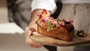 Una persona sostiene un pan con diferentes ingredientes sobre una tabla de madera.