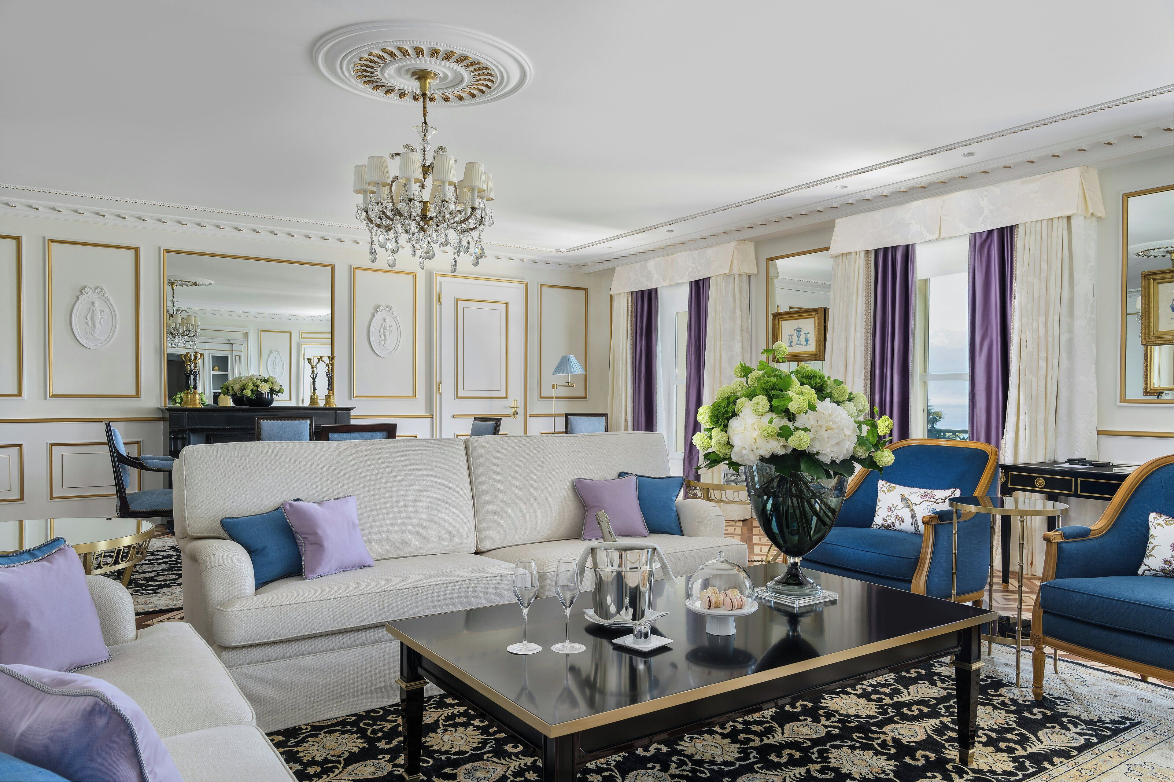 A spacious living room with a large sofa, a coffee table, and a chandelier.