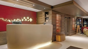 A reception area with a red wall, a reception desk, and a wooden wall with shelves.