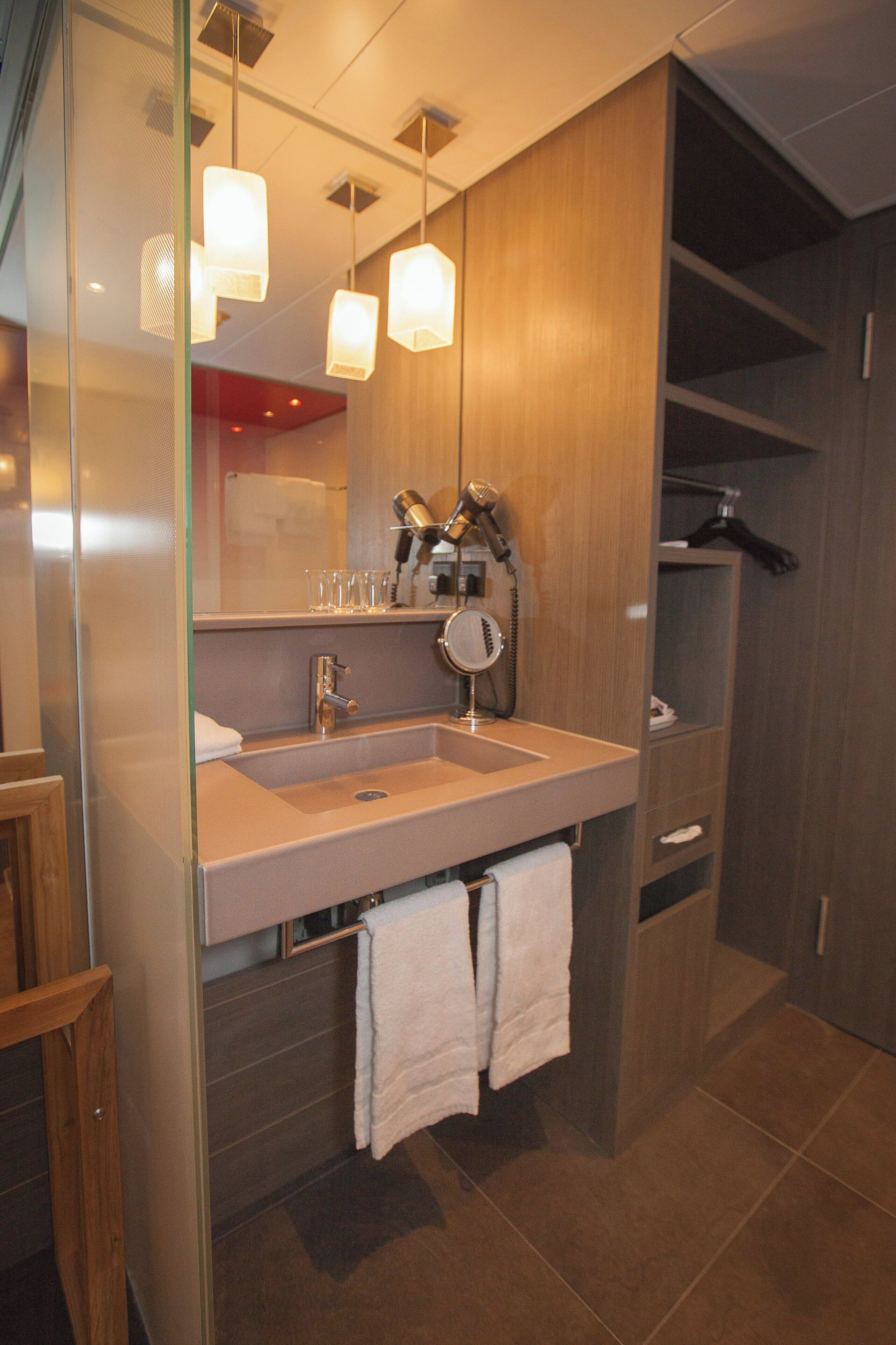 Un baño moderno con un lavabo amplio, espejo y perchero para toallas.