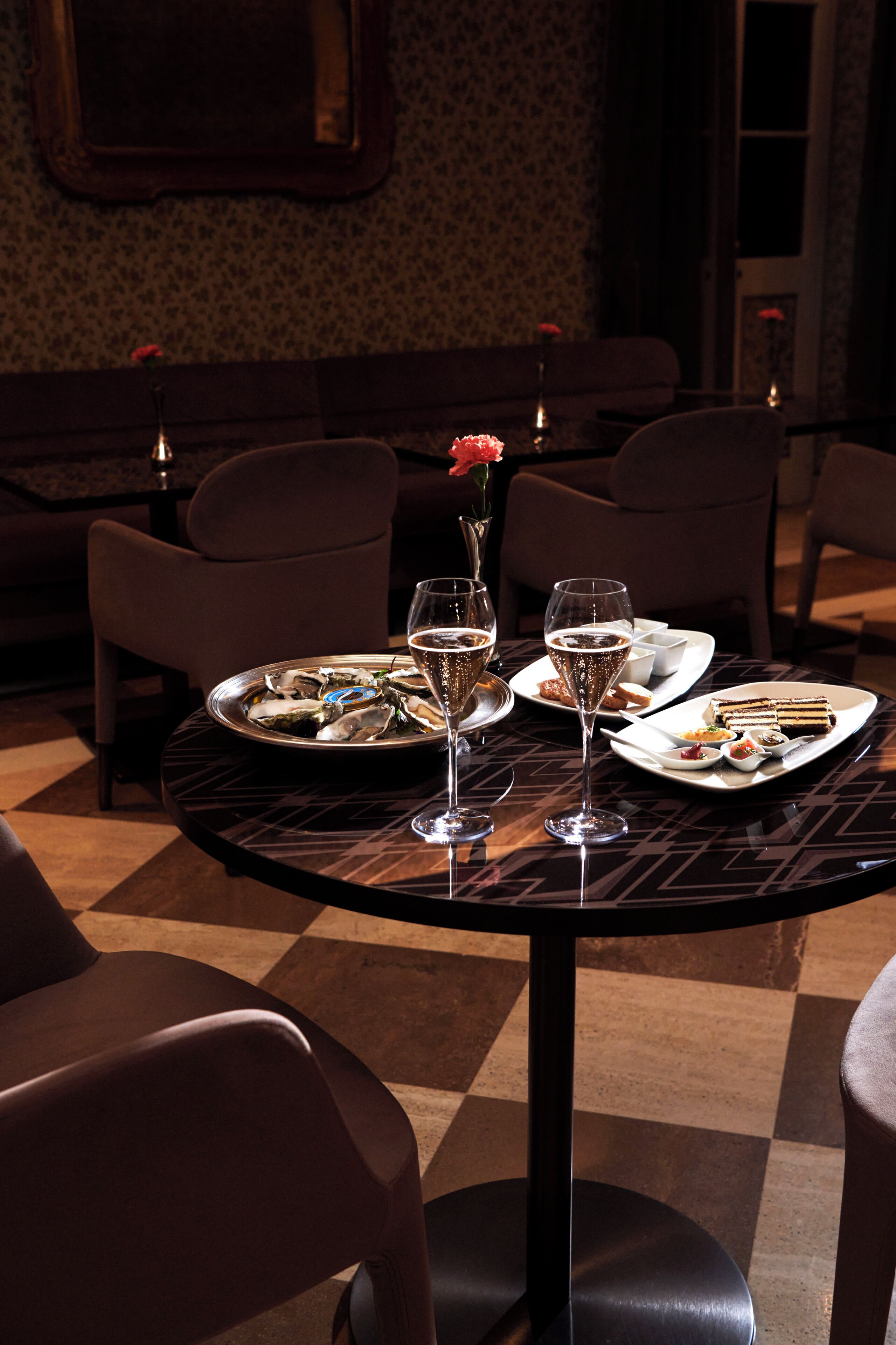 Une table à manger dressée avec des assiettes, des verres et un vase contenant une fleur.