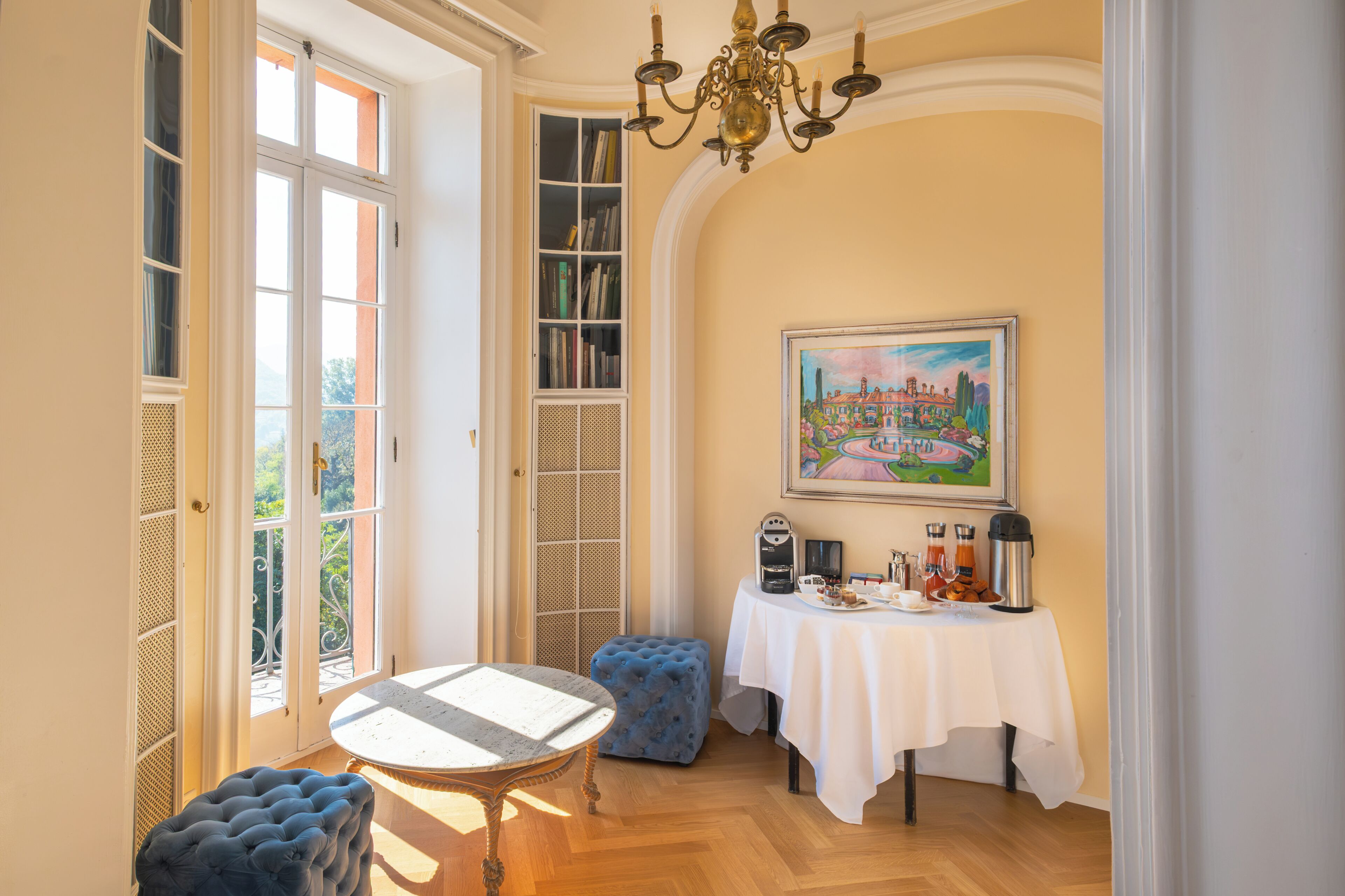 Une pièce avec une table mise pour le petit-déjeuner, une bibliothèque, un tableau et une vue par la fenêtre.