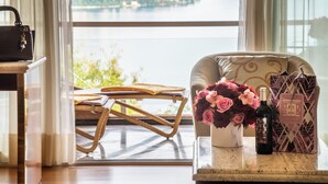 A view of a balcony with a chair, a table with a bottle of wine, and a vase of flowers.