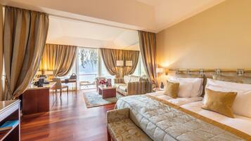 Habitación de hotel con una cama grande, un escritorio, un sofá y una silla. Cuenta con una ventana con cortinas, una lámpara y vistas al exterior.