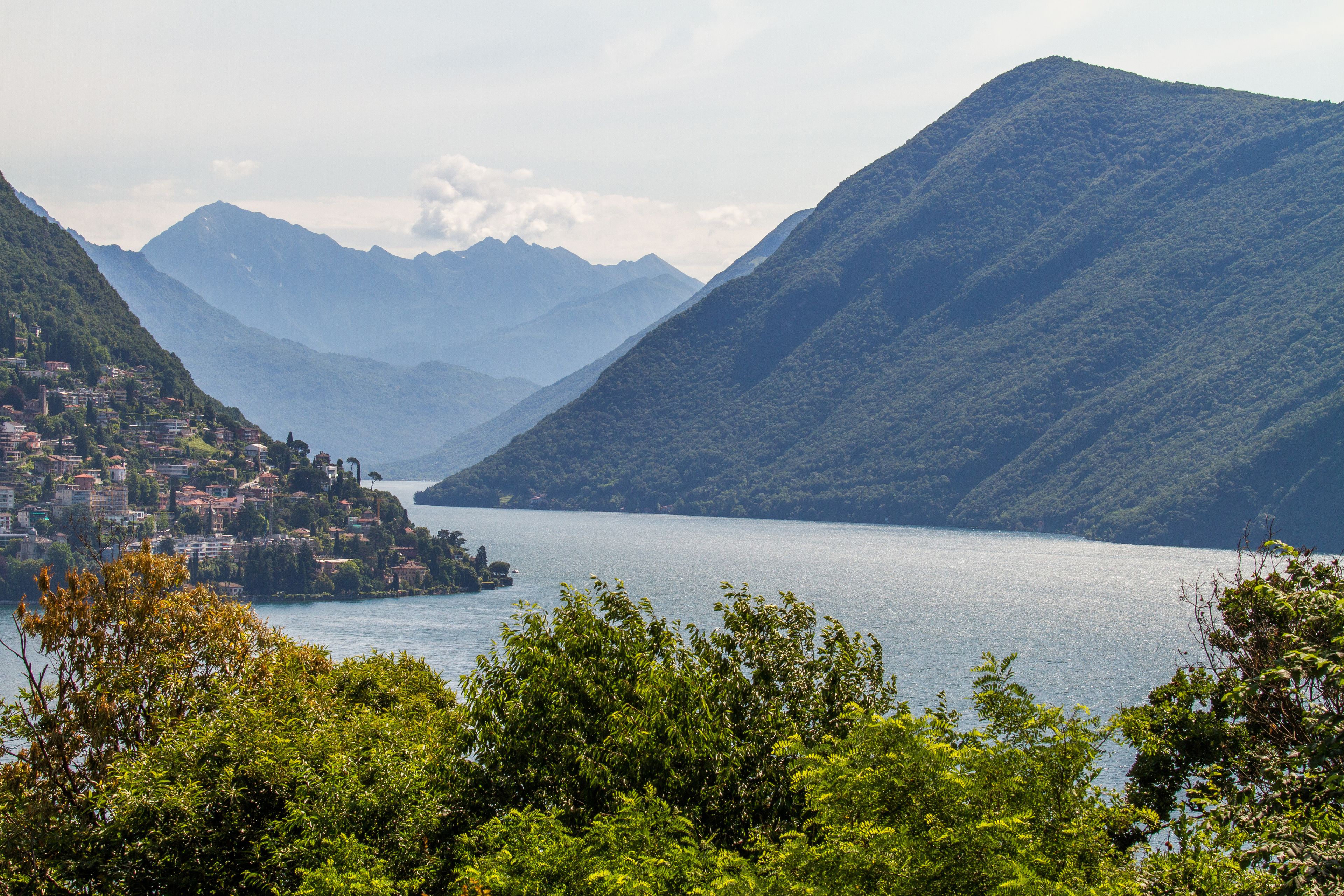 Un paysage montagneux avec un lac, une petite ville et une végétation luxuriante.