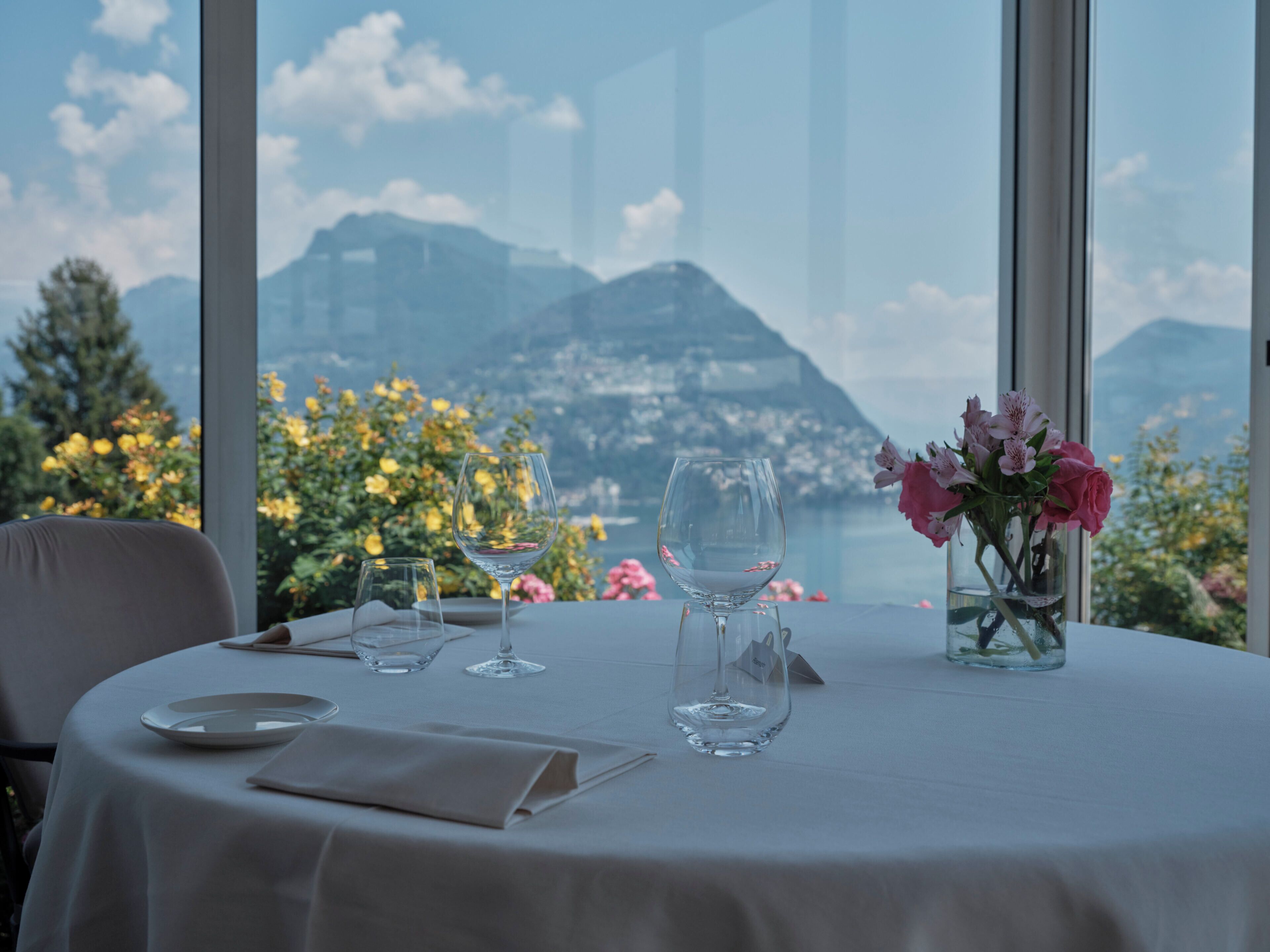 A table set for two with a view of mountains and a lake.