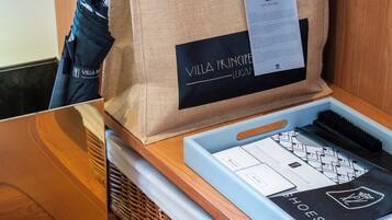 Un comptoir en bois sur lequel se trouve un sac noir et beige portant l’inscription « Villa Principi Lucan », ainsi qu’un plateau bleu contenant une boîte à chaussures et un document.