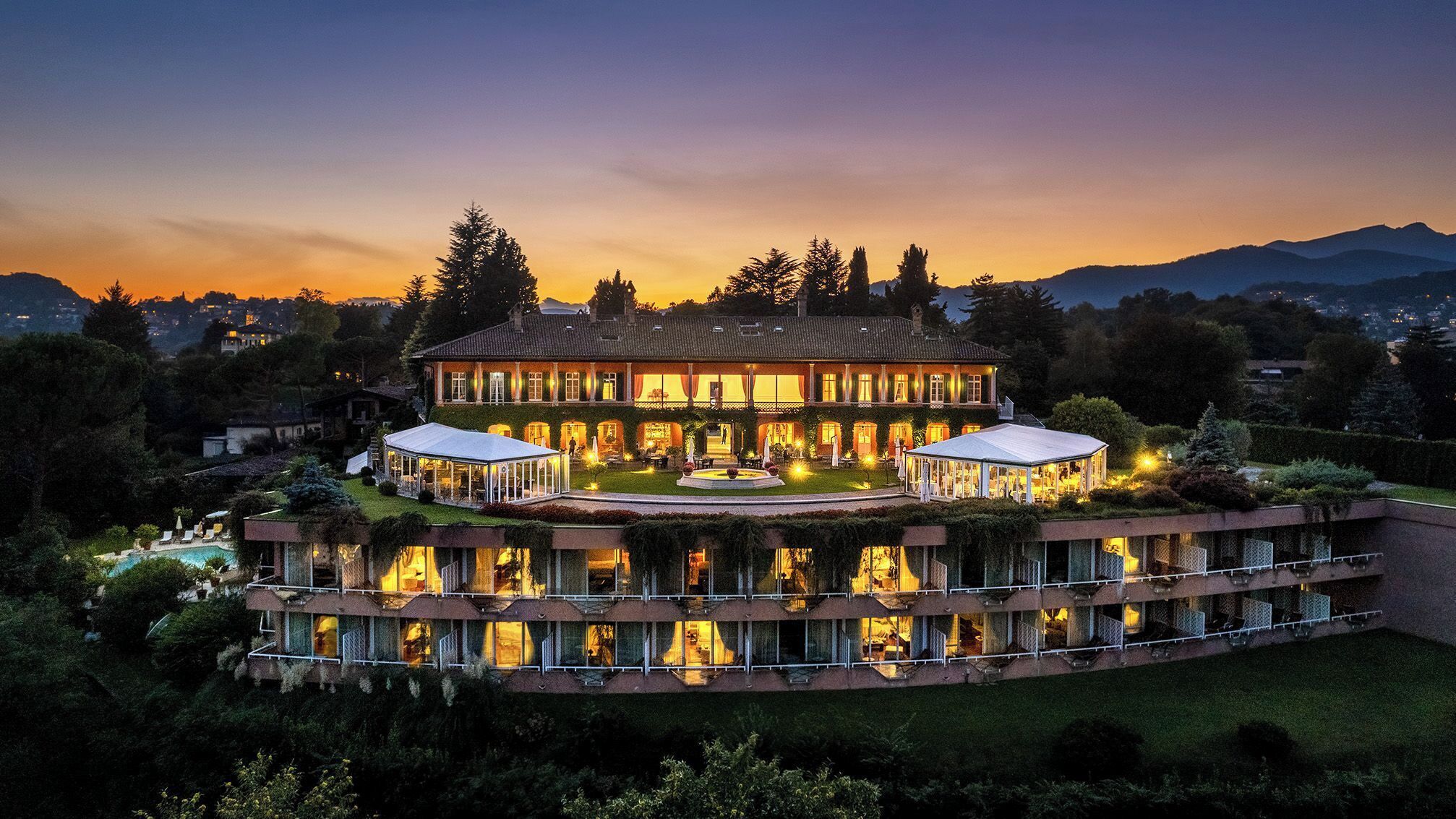 Ein großes, mehrstöckiges Hotel mit Innenhof, mehreren Balkonen und einem Poolbereich.