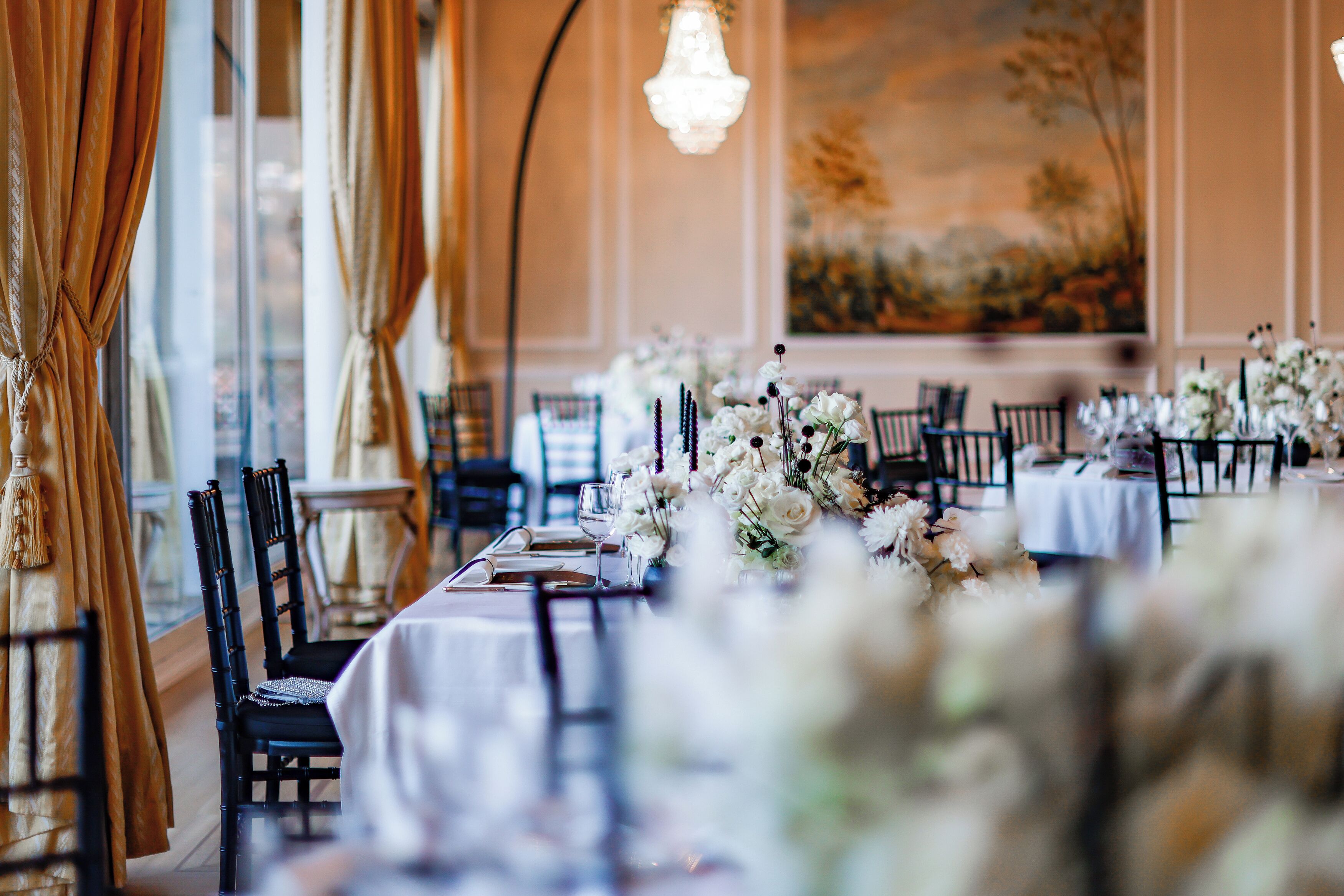 Une salle de banquet où les tables sont dressées pour un événement formel, avec des compositions florales et une décoration de table élégante.