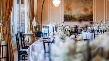 A banquet hall with tables set for a formal event, featuring floral centerpieces and elegant table settings.