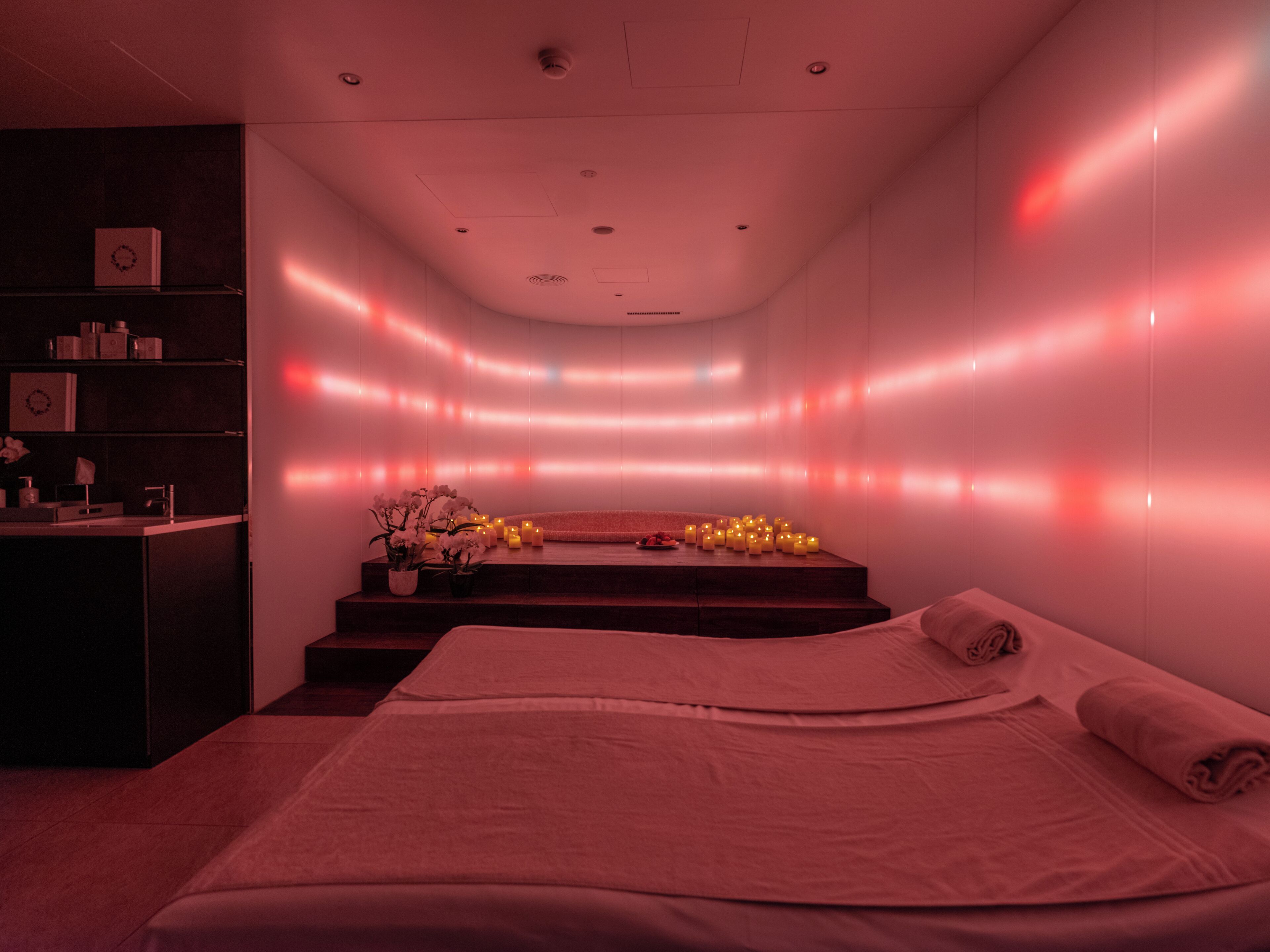 A spa room with a bed, a reception desk, and a wall with ambient lighting.