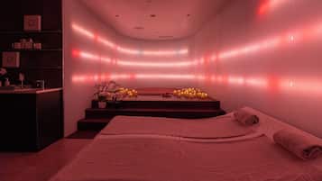 A spa room with a bed, a reception desk, and a wall with ambient lighting.