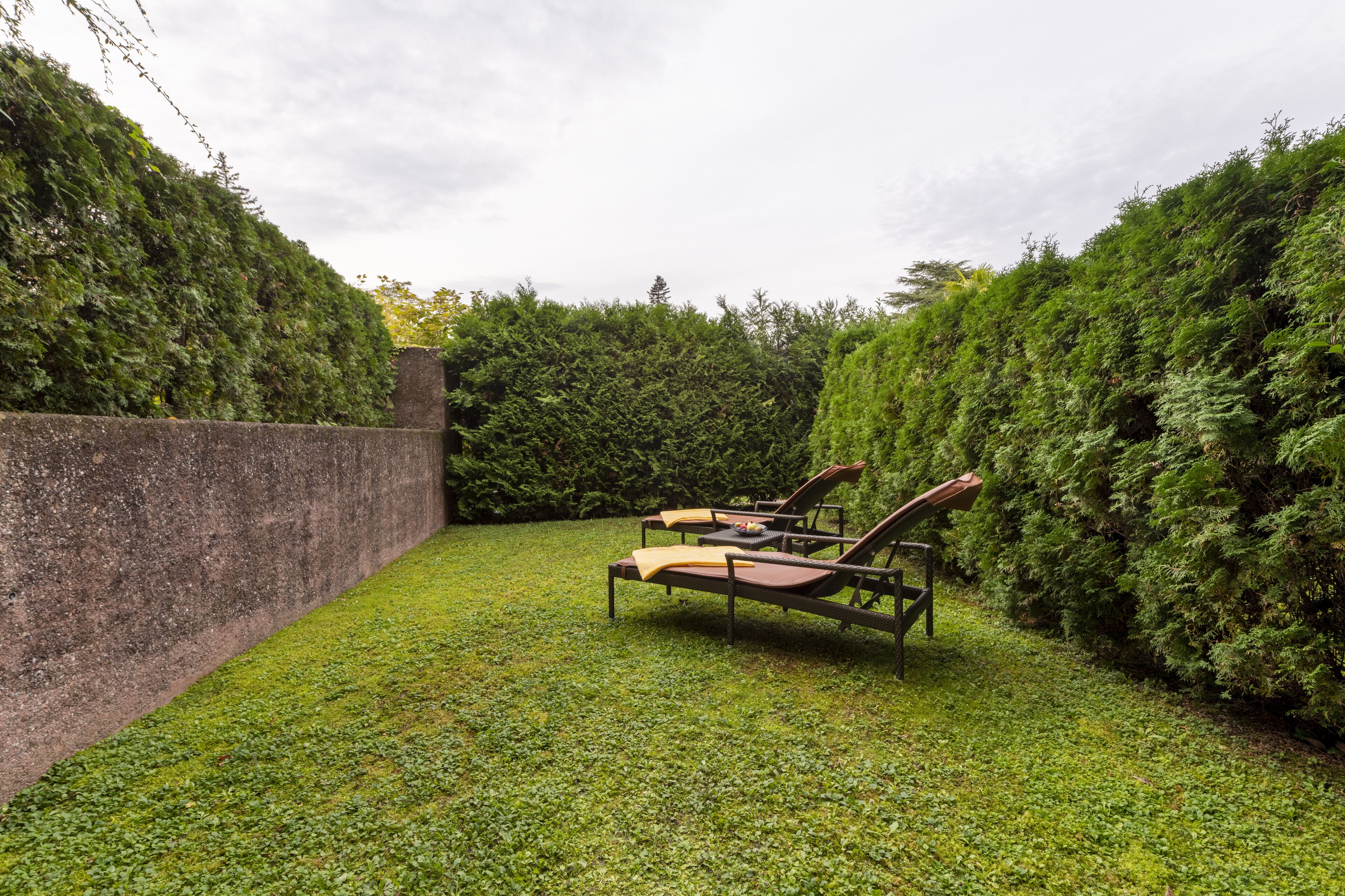 Un jardin avec deux chaises longues et un mur en pierre.