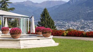 A gazebo with steps leading up to it, surrounded by potted plants and flowers.