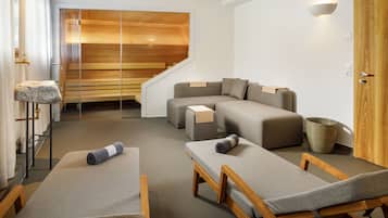 A modern living room with a sofa, two lounge chairs, a wooden staircase, and a large window.