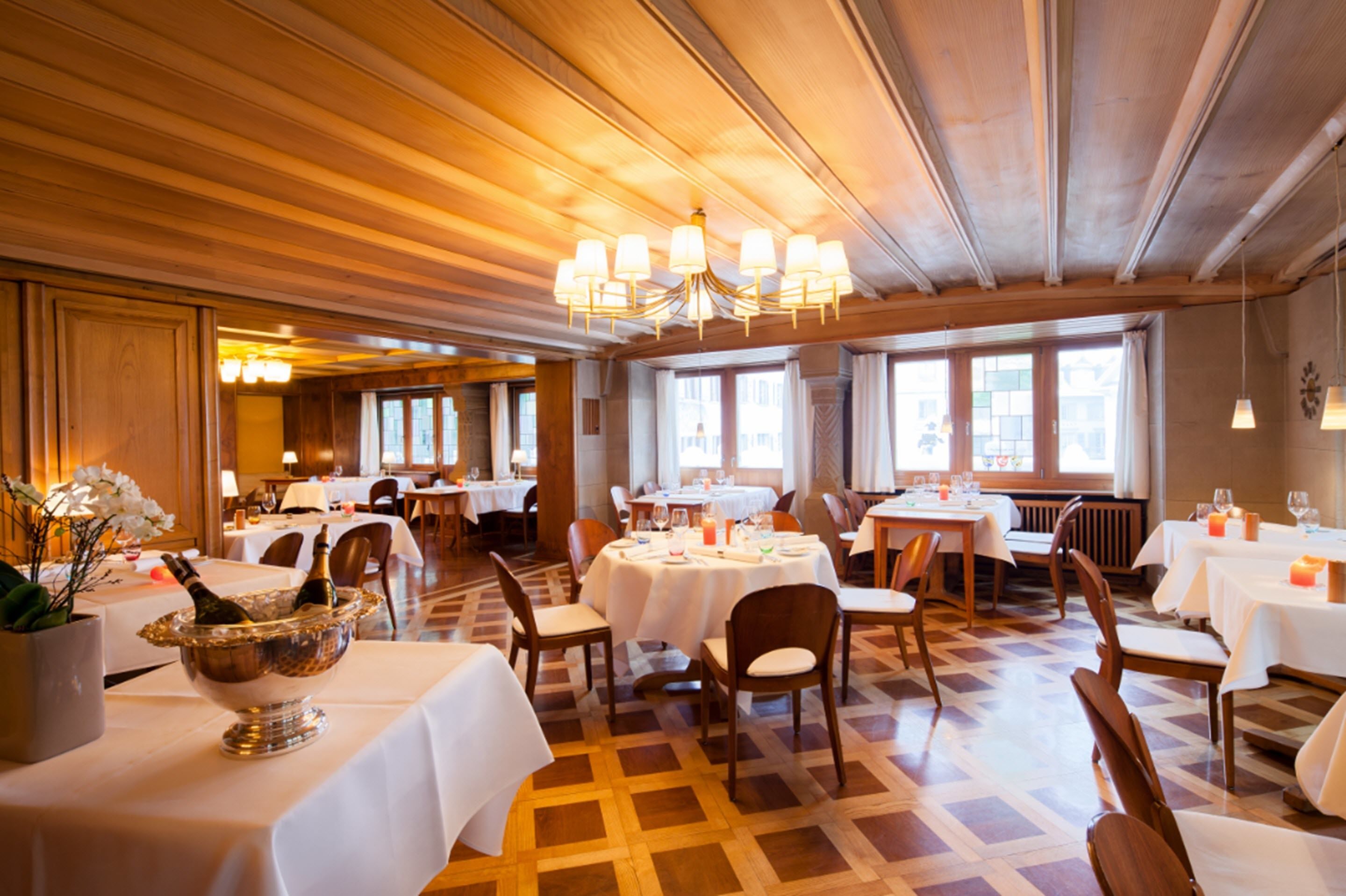 Un restaurante con paneles de madera, candelabros y mesas dispuestas para comer.