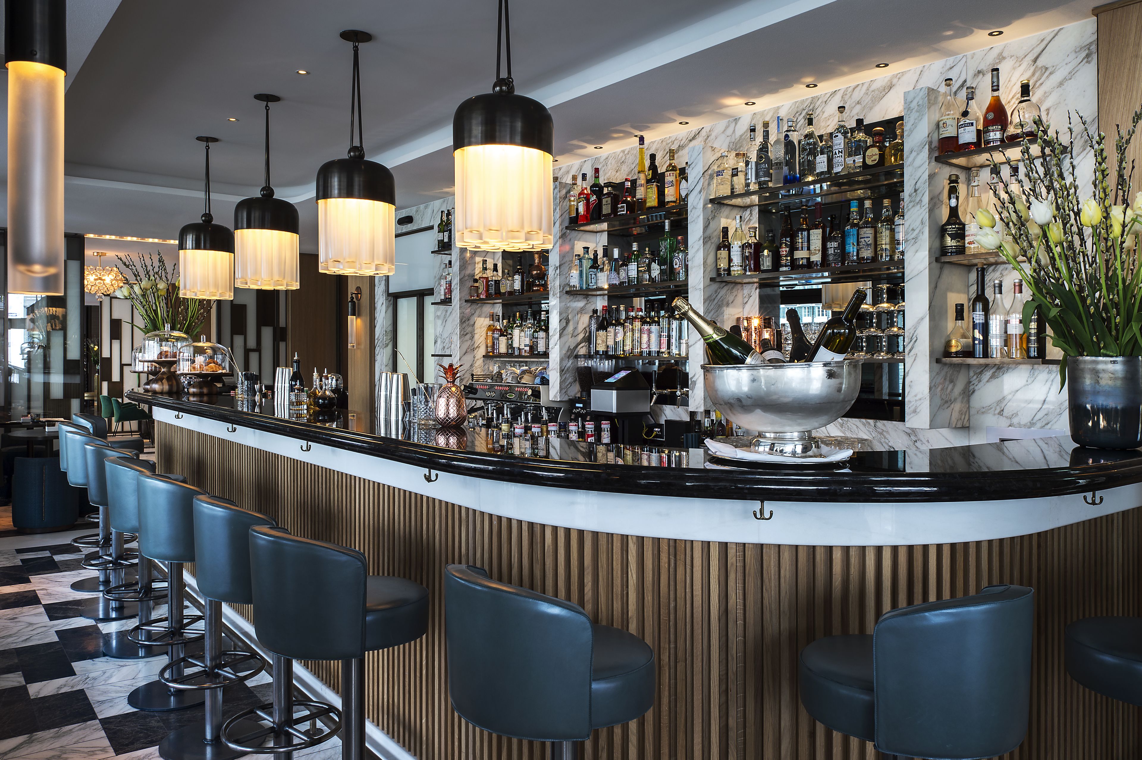 A bar area with a marble countertop, multiple liquor bottles, and bar stools.
