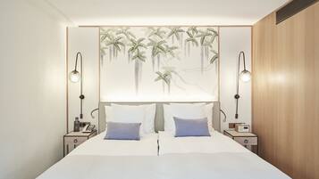A modern bedroom with a large bed, two bedside tables, a wall-mounted lamp, and a decorative headboard.
