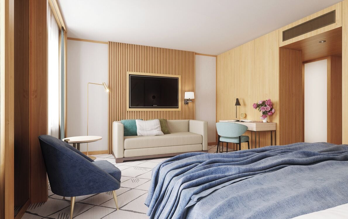 Ein modernes Hotelzimmer mit einem großen Bett, einer Sitzecke, einem Schreibtisch und einem an der Wand befestigten Fernseher.