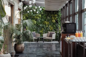 Um espaço interior moderno com parede verde, área de estar e bar com petiscos.