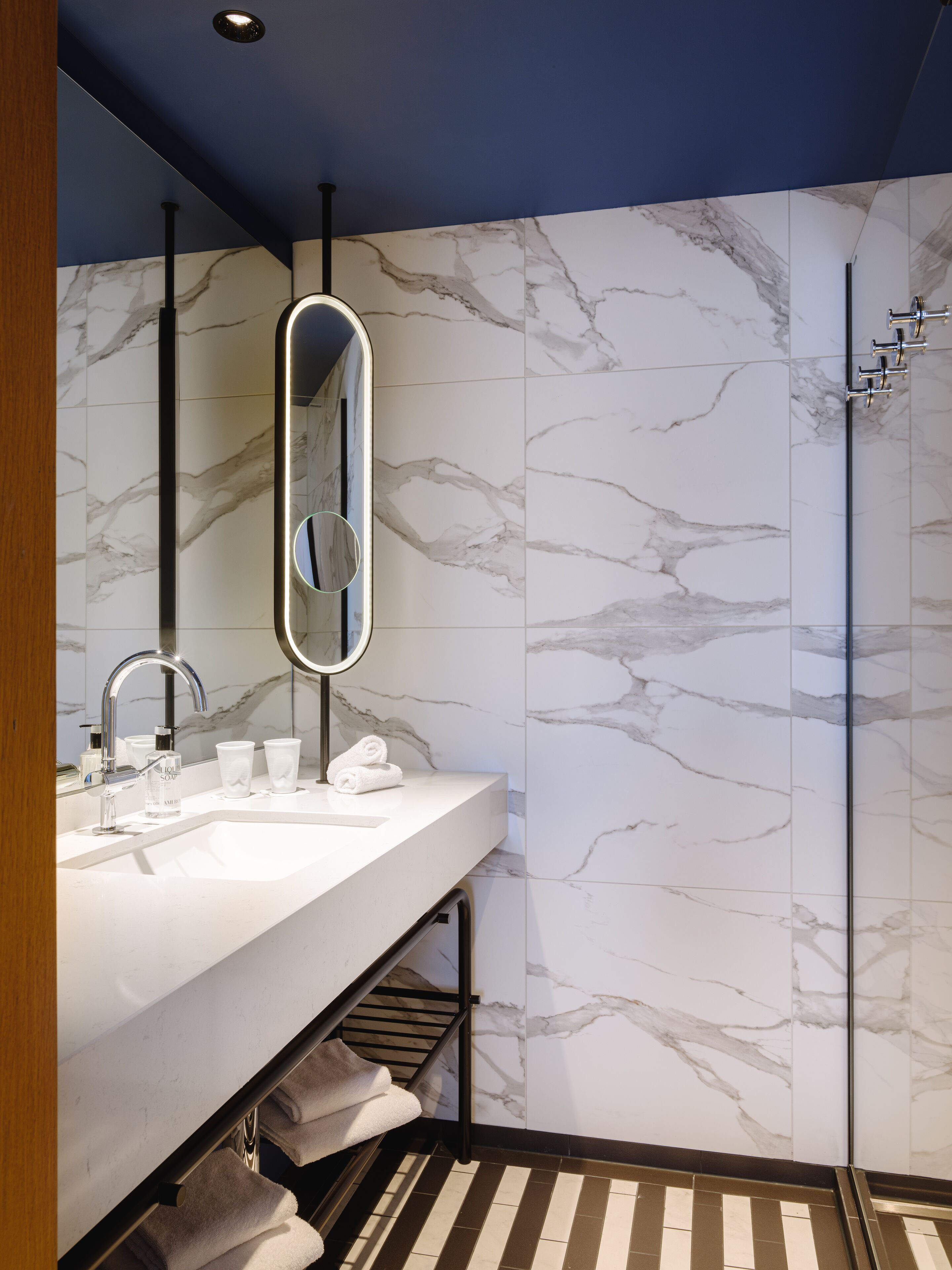 Un baño moderno con salpicadero de mármol, un espejo grande, un lavabo y una ducha.