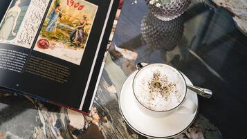 Un libro abierto sobre una mesa de mármol, con una taza de café y un jarrón de flores.