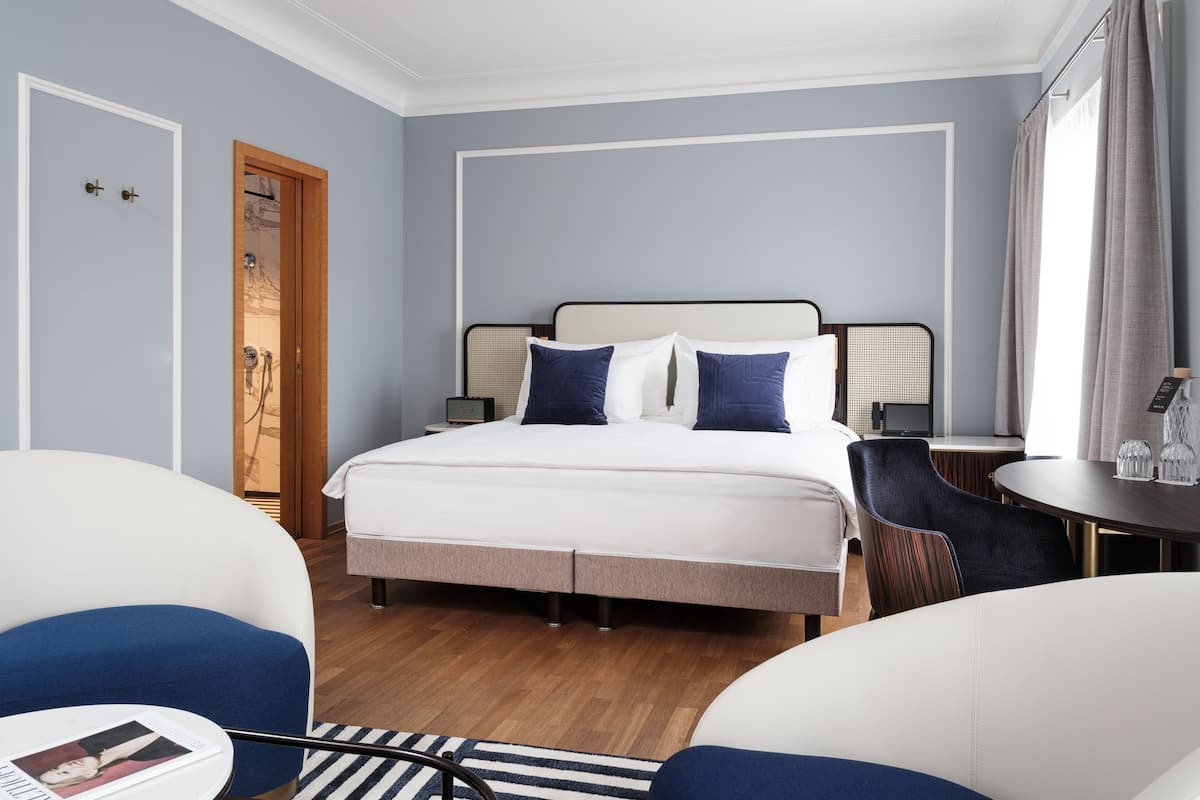 Una habitación de hotel con una cama, una silla, una mesa y una mesita de noche.