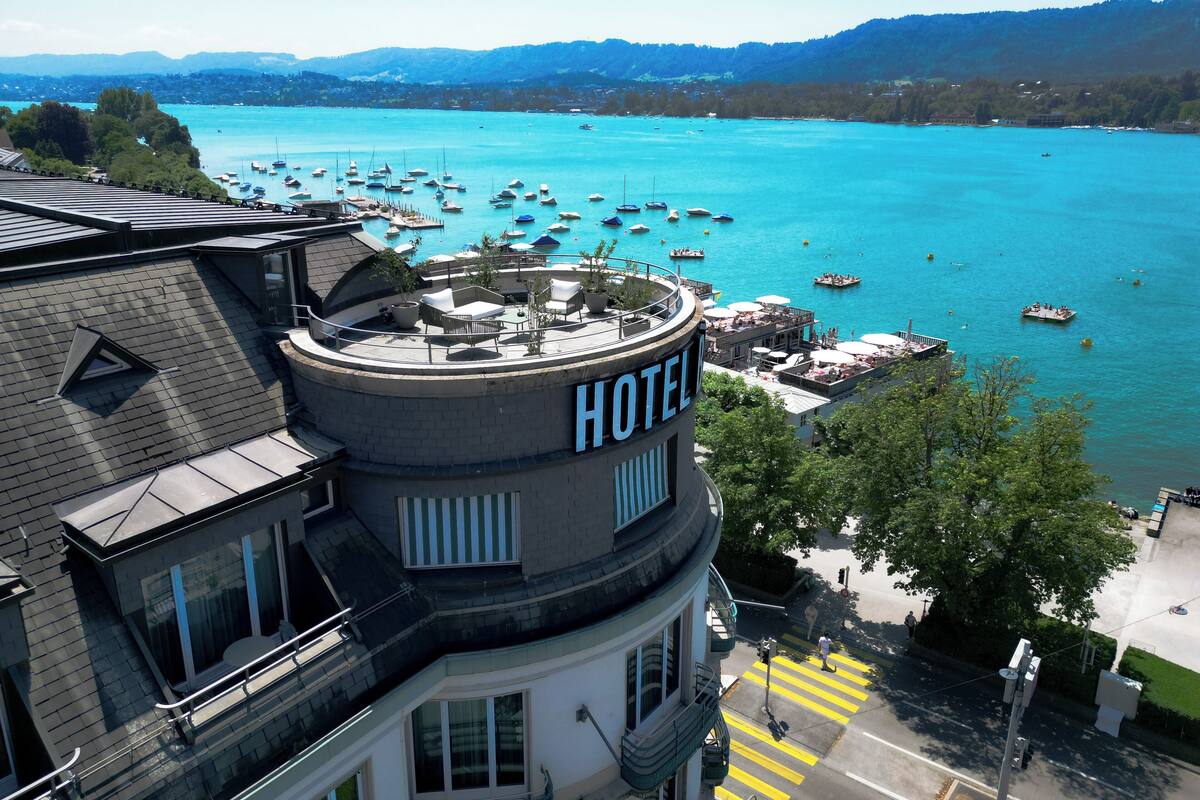 Un hotel con terraza en la azotea y vistas a una bahía con barcos.