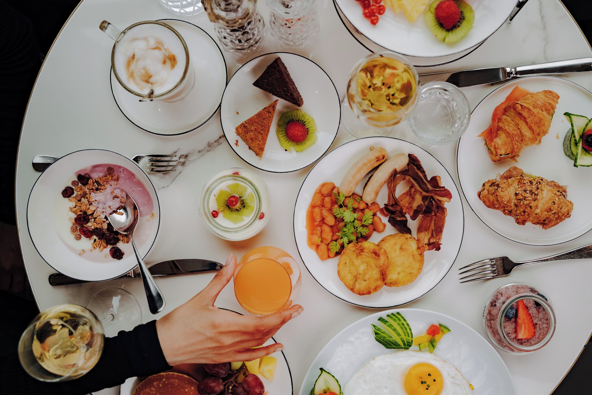 A breakfast table with various dishes including eggs, bacon, and pastries.