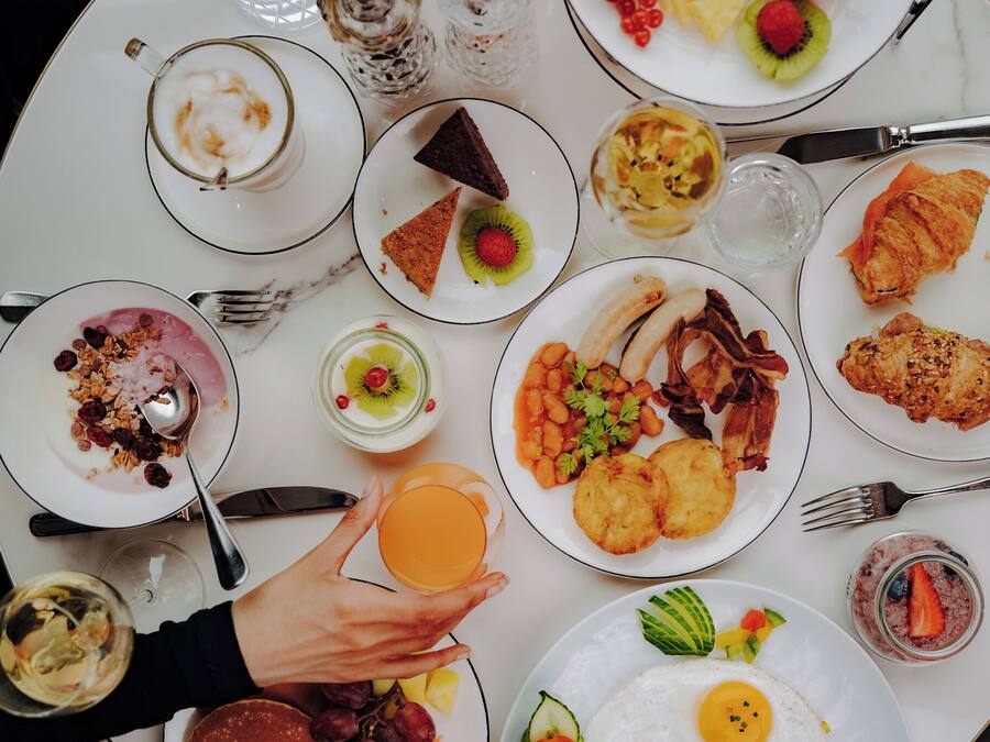 A breakfast table with various dishes including eggs, bacon, and pastries.