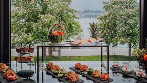 Ein Buffet mit verschiedenen Speisen und einem schönen Blick auf einen See und Bäume.