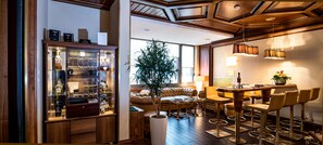 A well-lit bar area with stools, a large potted plant, and a seating area with a sofa and chairs. - Hotel Sternen Oerlikon (Zürich)