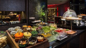A buffet with various food items and condiments, including jars of pickles, a salad bar, and a meat station.