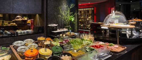 A buffet with various food items and condiments, including jars of pickles, a salad bar, and a meat station.