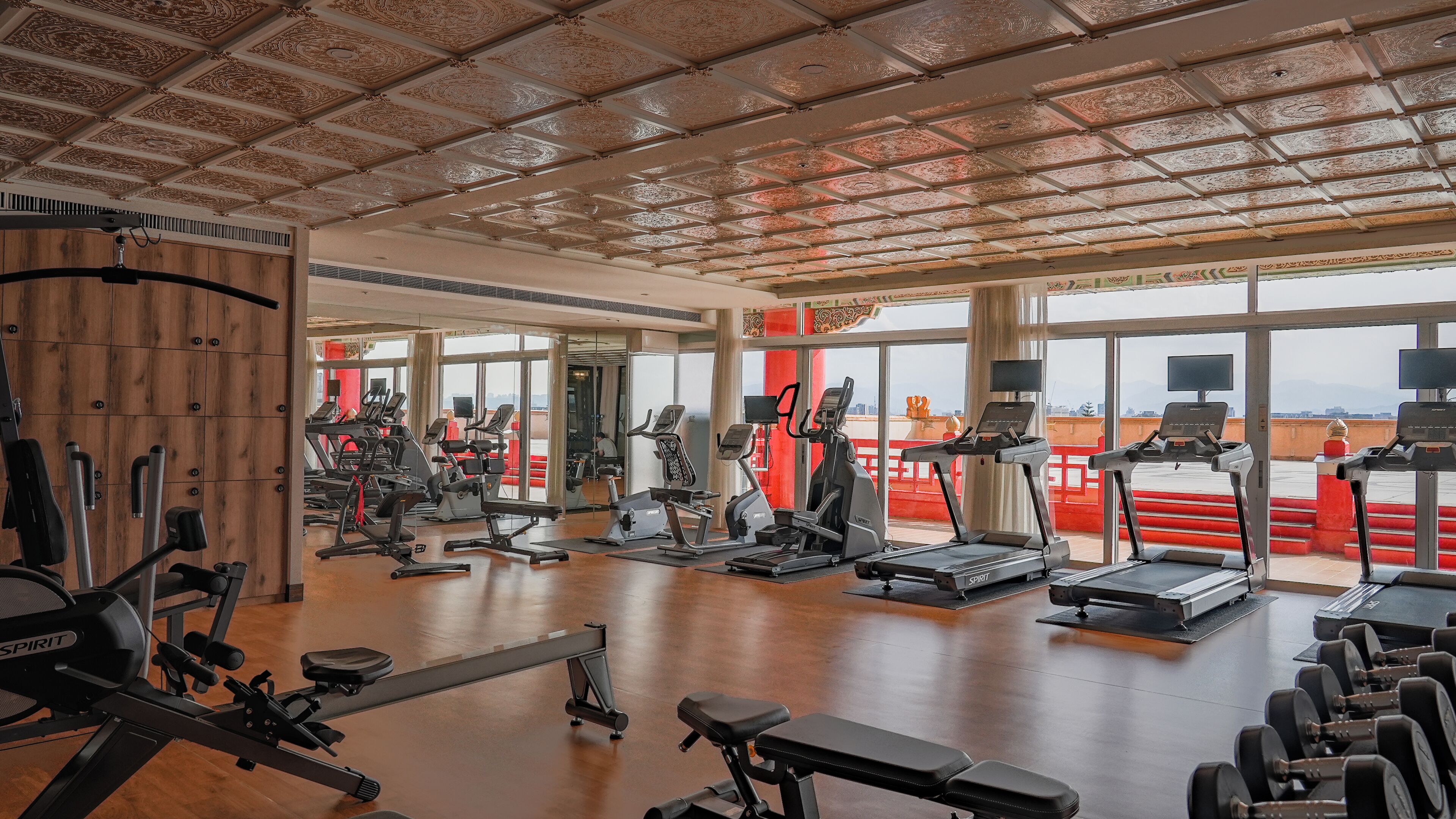 Une salle de sport spacieuse, dotée de divers appareils d’exercice, de grandes fenêtres et d’un plafond haut.