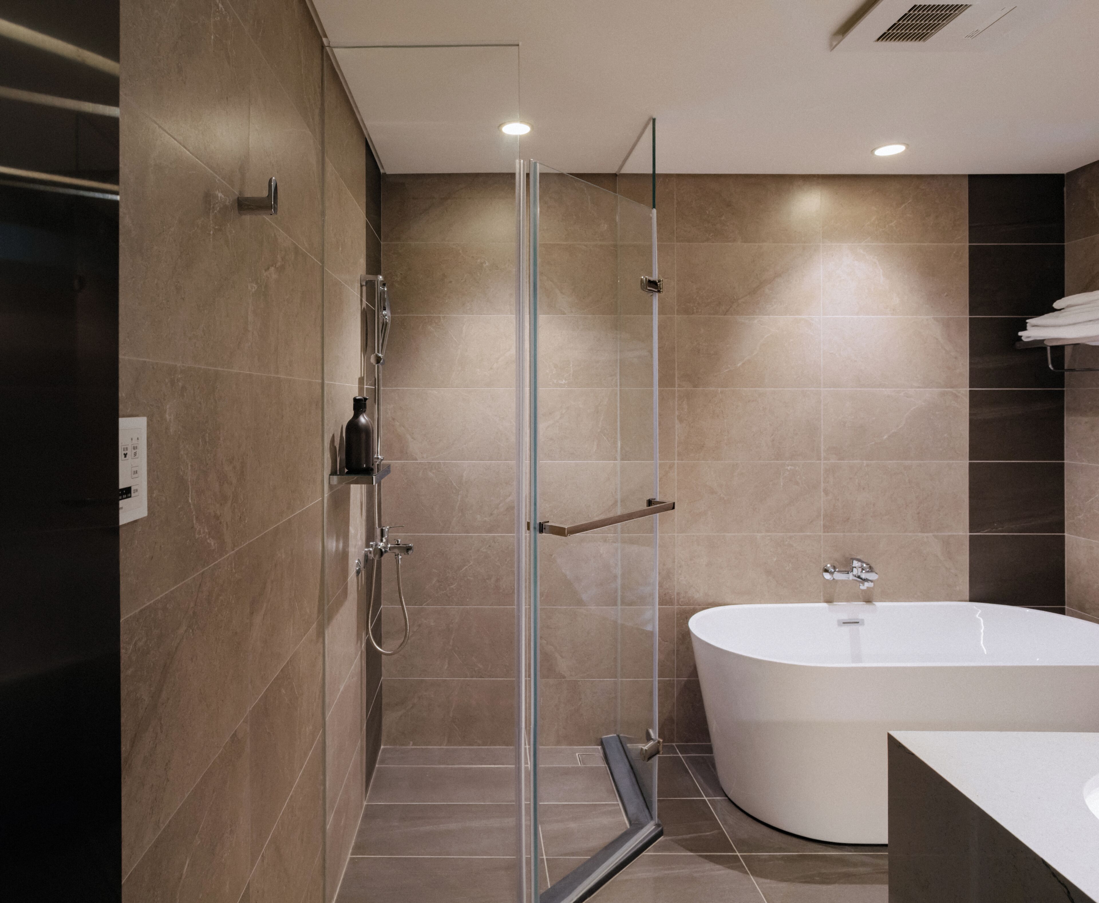 Un baño moderno con ducha de vidrio, una bañera independiente y un toallero de pared.
