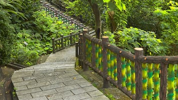A stone staircase with a wooden railing, surrounded by lush greenery.
