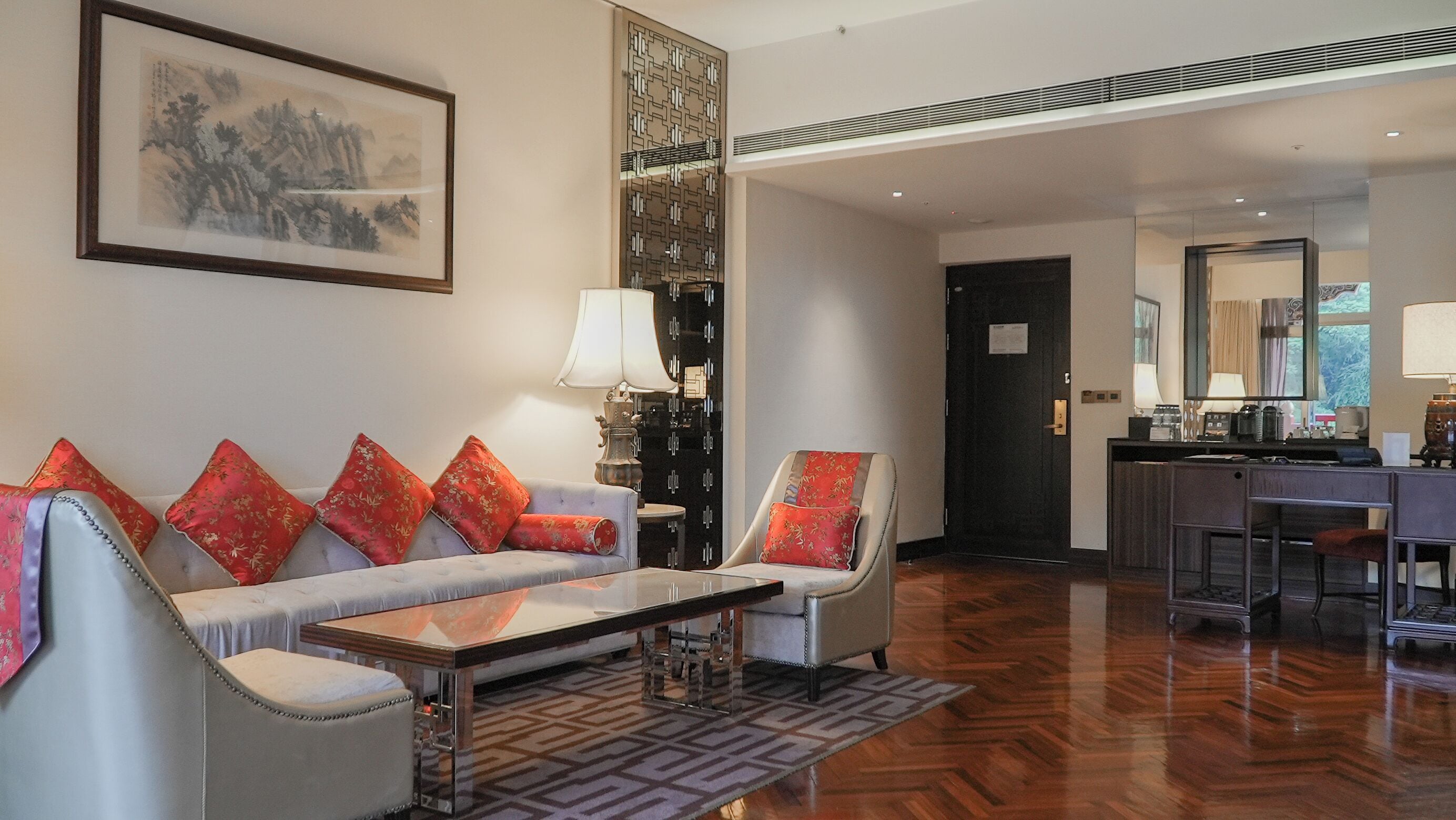 A modern hotel lobby with a sofa set, a coffee station, and a large mirror.
