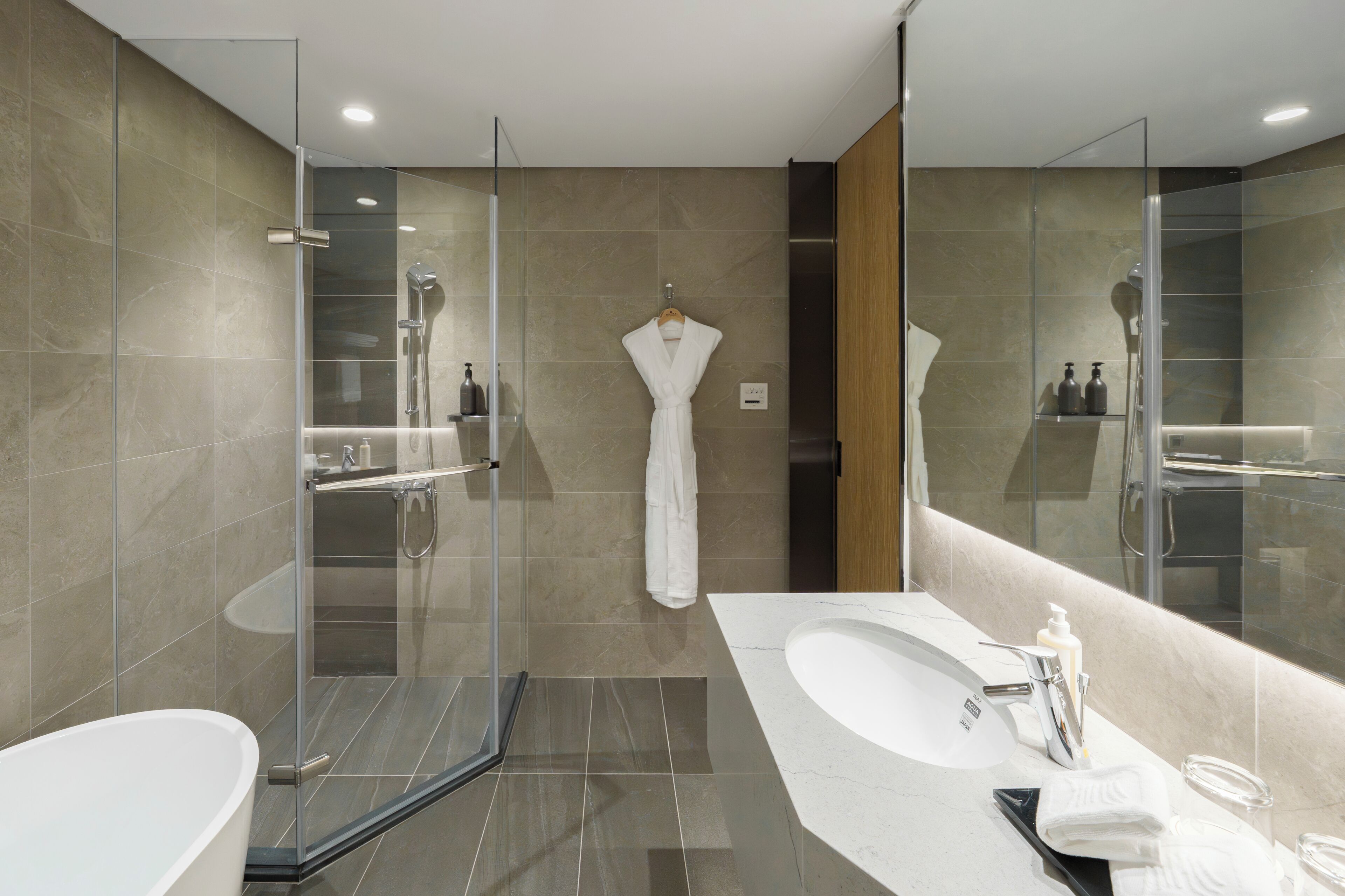 A modern bathroom with a glass-enclosed shower, a standalone bathtub, and a vanity with a large mirror.