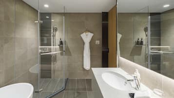 Un baño moderno con ducha envuelta en vidrio, una bañera independiente y un tocador con un espejo grande.