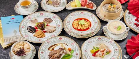 Una mesa dispuesta con diversos platos, incluyendo un tazón de sopa, un plato con carne y una taza de té.
