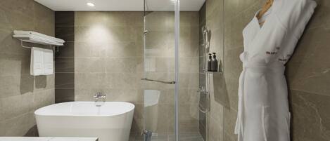A modern bathroom with a bathtub, shower, and a robe hanging on the wall.