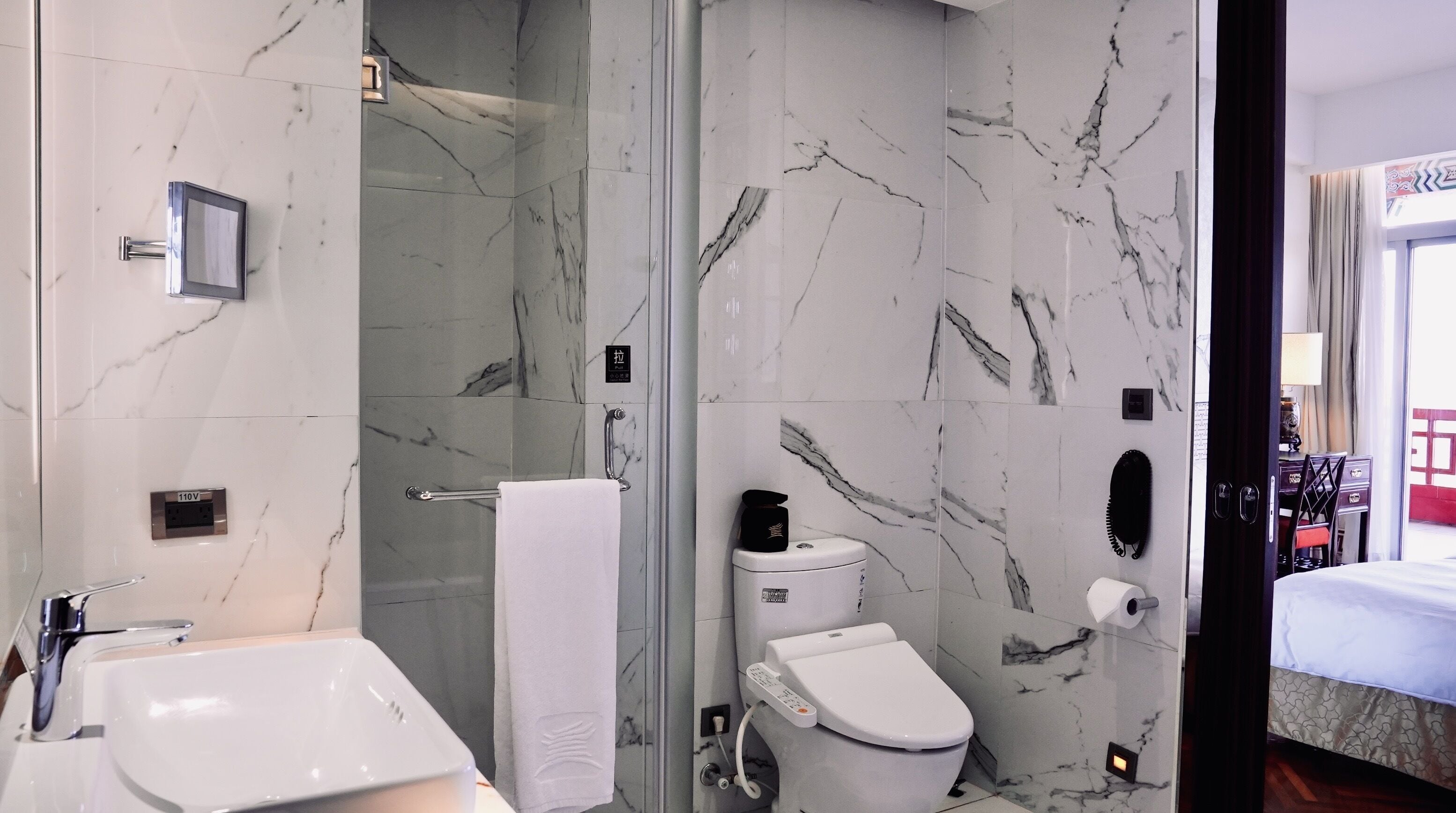 A modern bathroom with a glass shower enclosure, a white toilet, and a sink with a mirror.