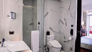 A modern bathroom with a glass shower enclosure, a white toilet, and a sink with a mirror.
