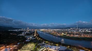 A cityscape at dusk with a river, bridges, and a prominent tower.